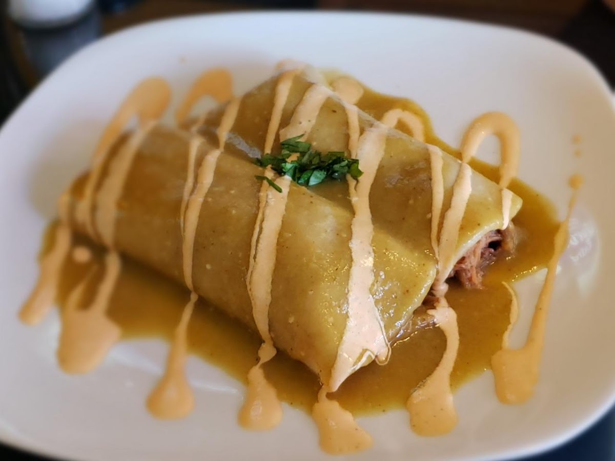 A wet burrito finished with tomatillo sauce and chipotle crema