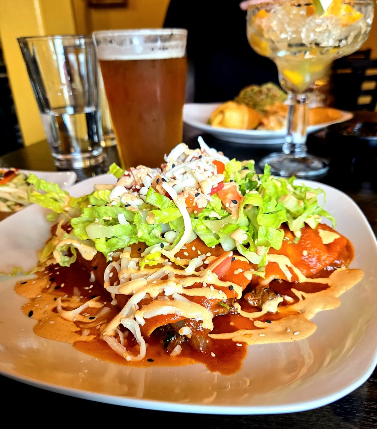 House enchiladas topped with crema, lettuce and pico, with a margarita